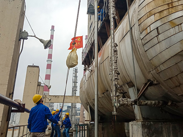 5月10日中午，在動(dòng)力車間三期工藝除氧器地面，黨員突擊隊(duì)隊(duì)員用滑輪往工藝除氧器平臺(tái)運(yùn)送鋼絲網(wǎng)，用以纏繞新填料.jpg