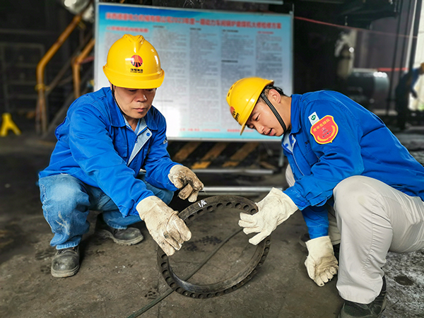 圖三：12日下午14時(shí)，在一期磨煤機(jī)廠房，陜西省技術(shù)能手姬霄給青工張跟潮講解磨煤機(jī)搖臂曲拐內(nèi)環(huán)及動(dòng)作原理。.jpg
